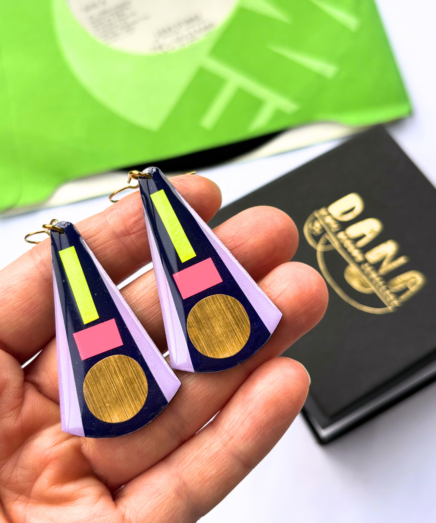 KAY in deep navy blue, neon pink, neon yellow, lilac, gold